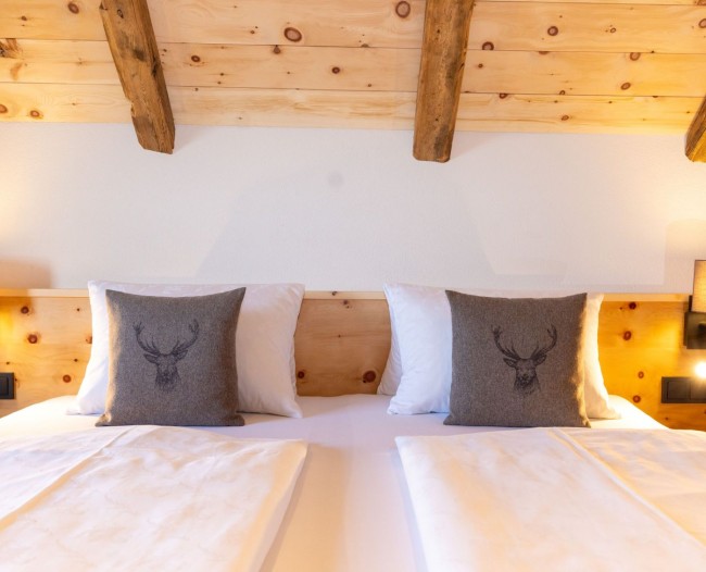 Doppelbett aus Zirbenholz und Hirsch-Zierkissen