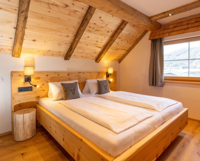 Schlafzimmer mit Doppelbett aus Zirbenholz und Balkon