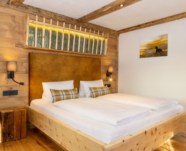 Schlafzimmer mit Doppelbett aus Zirbenholz und Futterkrippe